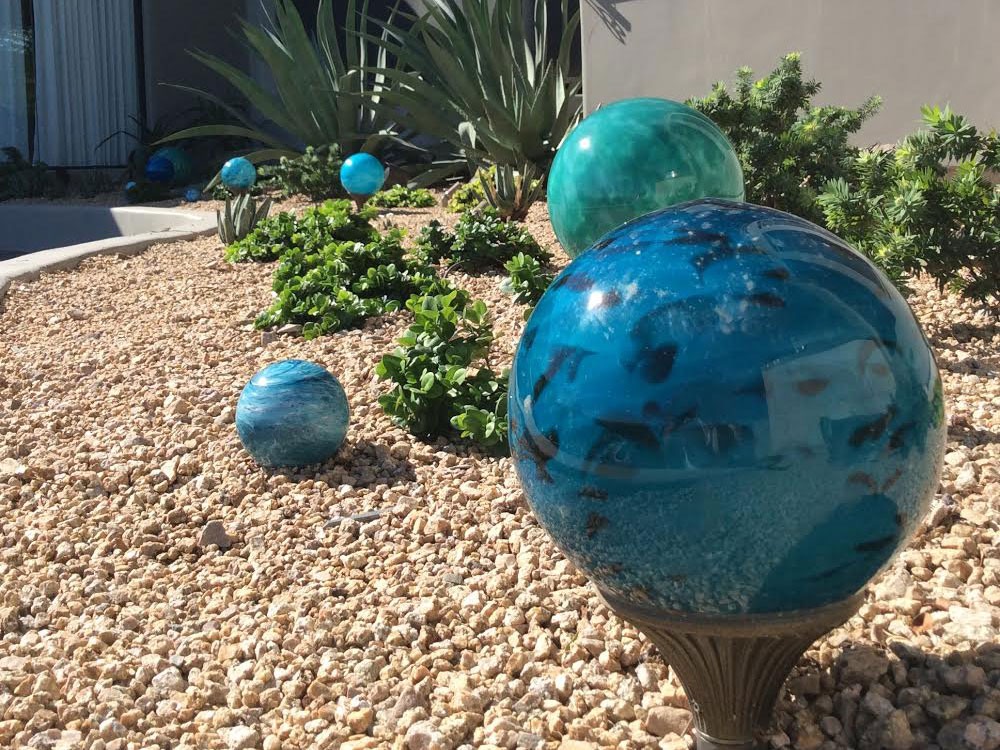Cool Blue 8 inch and 4 inch nightorbs on stones in desert landscape provide exterior lighting around house